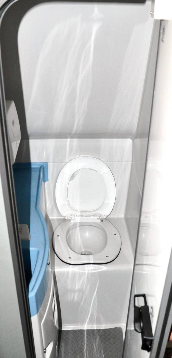 Bus toilet interior view showing compact FRP cabin with western toilet