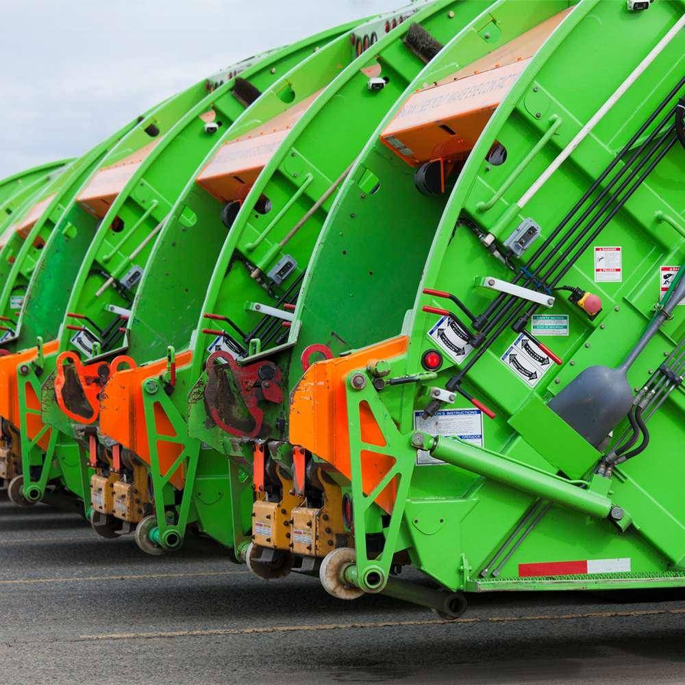 Fleet of garbage compactor trucks with hydraulic bin lifters ready for deployment
